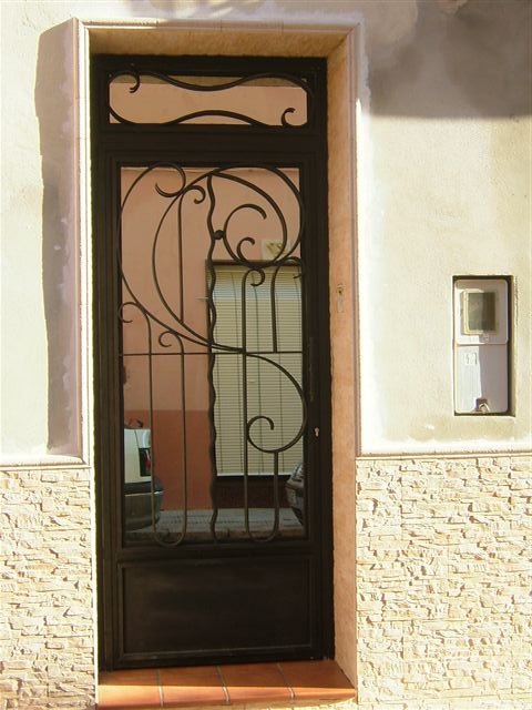 Puerta de una hoja con fijo en parte superior adornos trabajados con la fragua de una manera artesanal. Diseo personalizado.Trabajo laborioso y artesanal bien ejecutado.